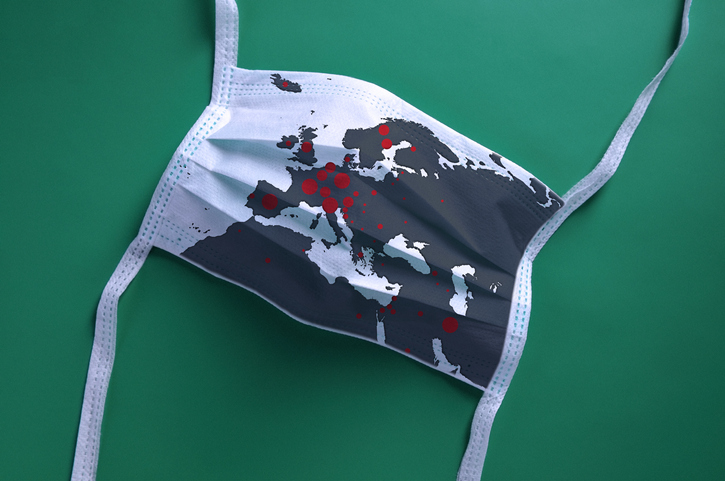 White face mask with a map of Europe is lying on a green background